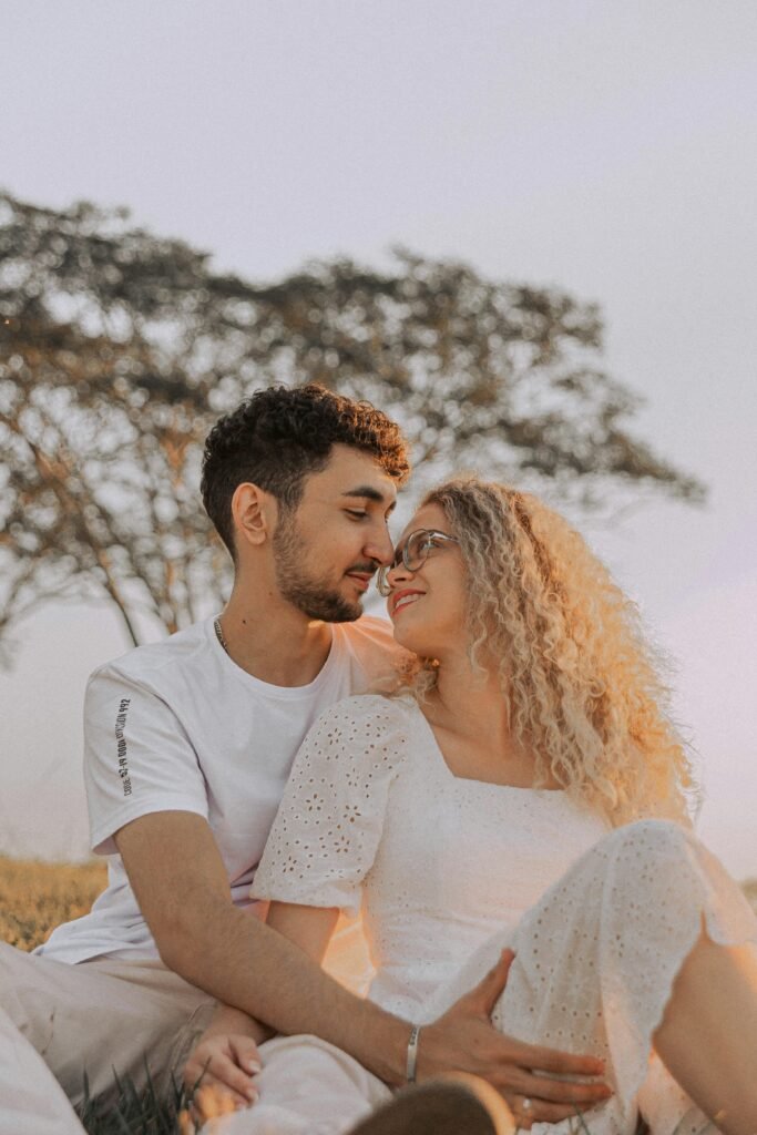 A happy couple sitting and embracing in a sunny outdoor setting.